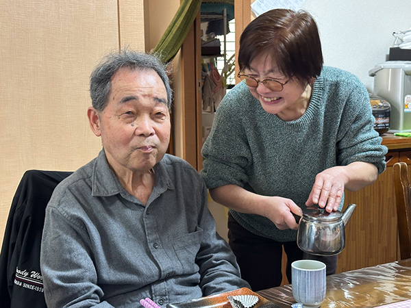 お茶を注ぐ女性と笑顔の老人