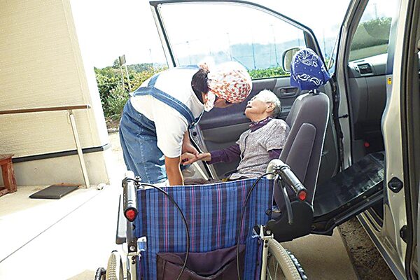 デイケアサービスで老人の女性を送迎する男性